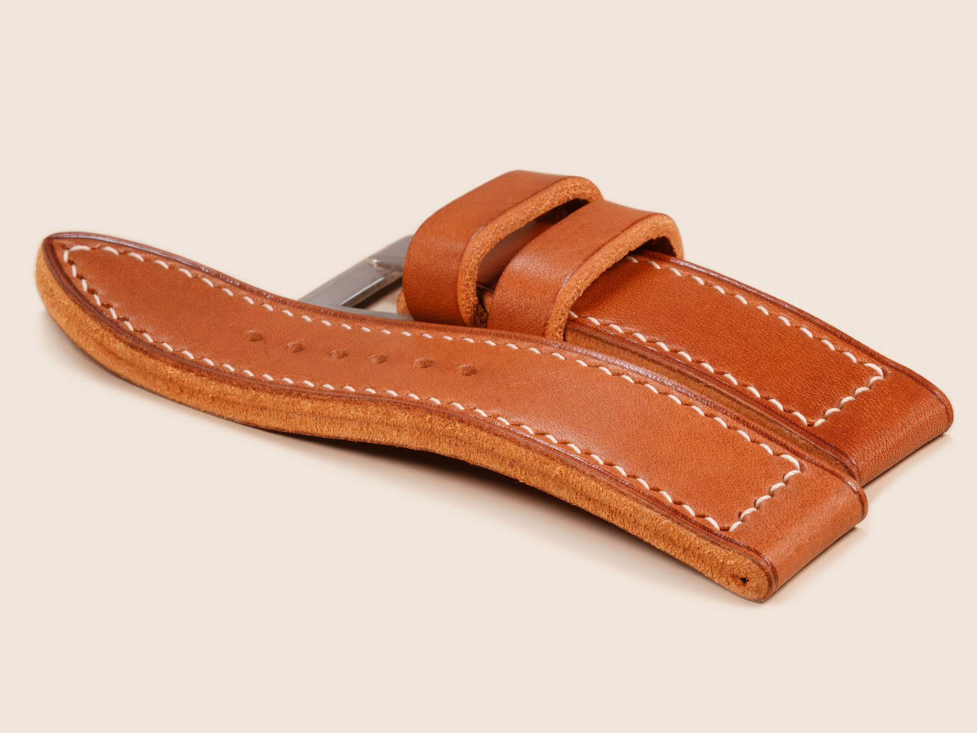 Thick Panerai strap in vintage tan leather laid flat inside a light box setup.