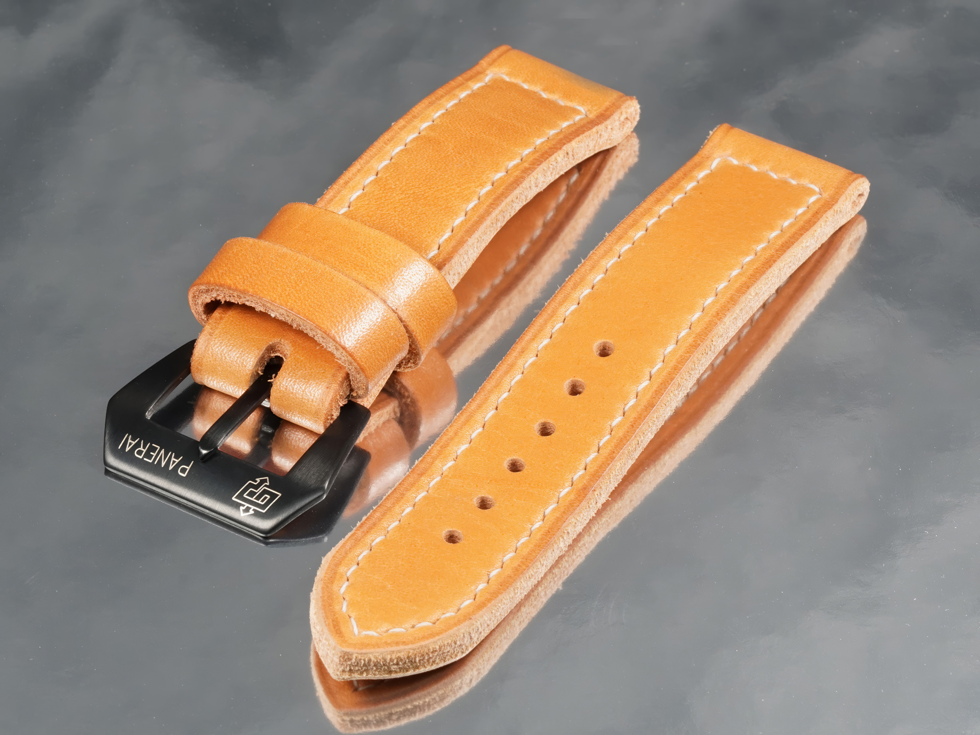 Flat lay of handcrafted orange tan leather strap for Panerai PAM05218 with black pin buckle