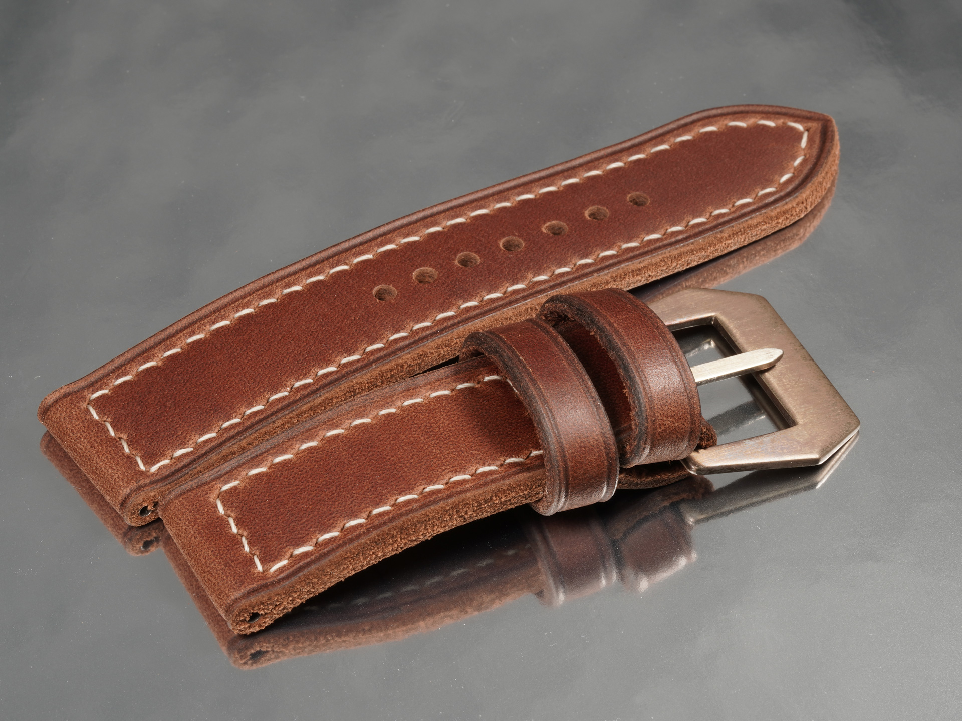 Macro detail of rust brown aged leather strap and sewn in pin buckle